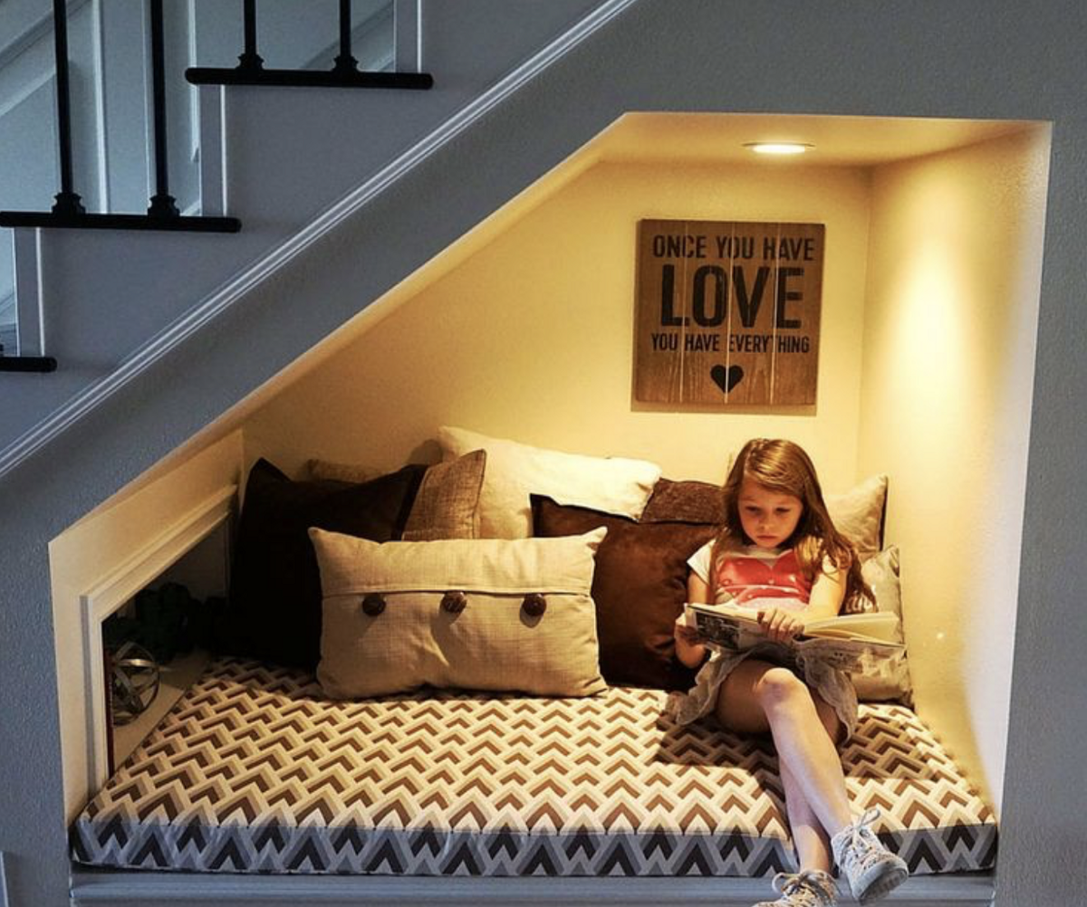 Столько места найти. Спальное место под лестницей. Домик под лестницей для ребенка. Уютный уголок под лестницей. Уголок для чтения под лестницей.