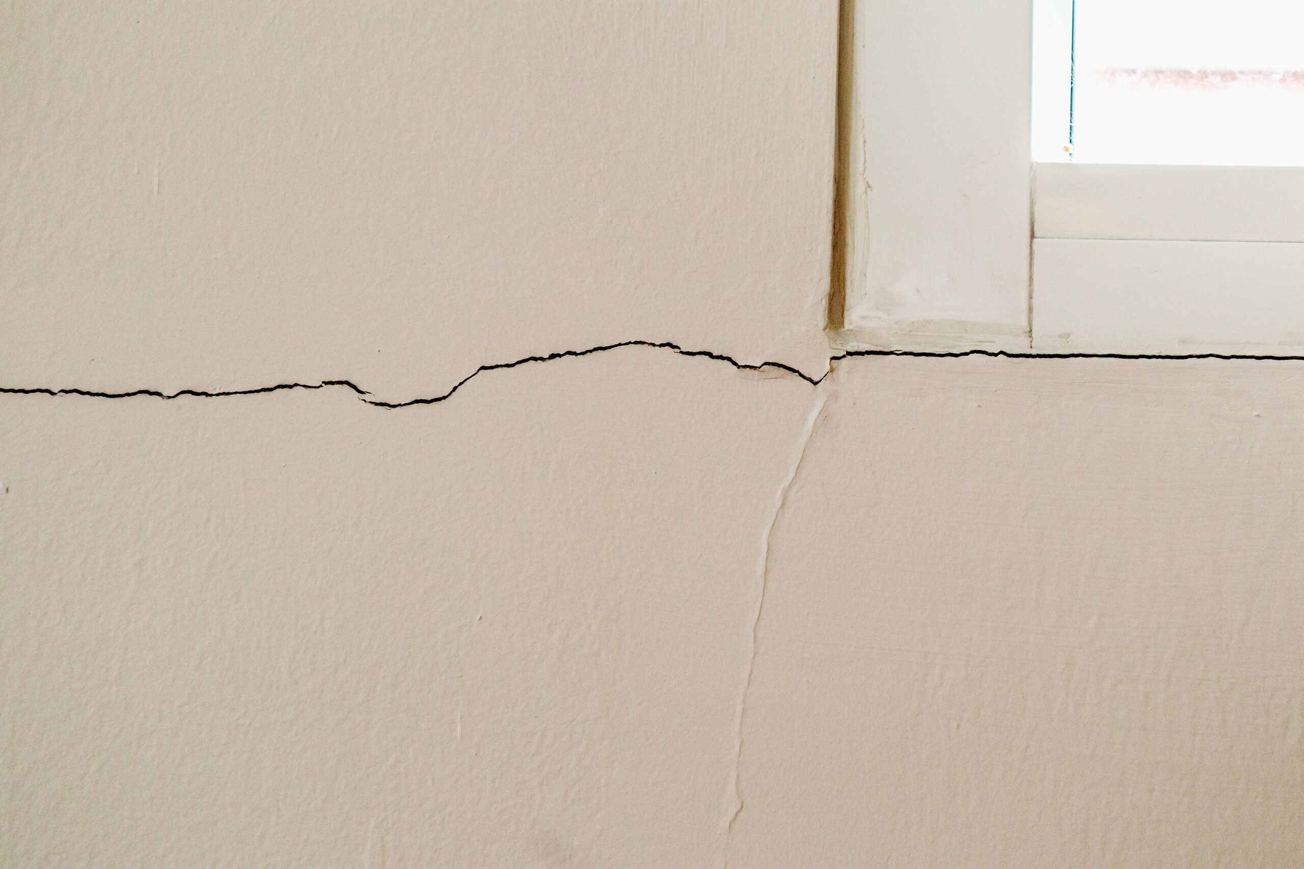 Трещин день. Потрескалась штукатурка около окна. Поврежденная стена. Cracked House Wall. Identifying cracks in Walls.