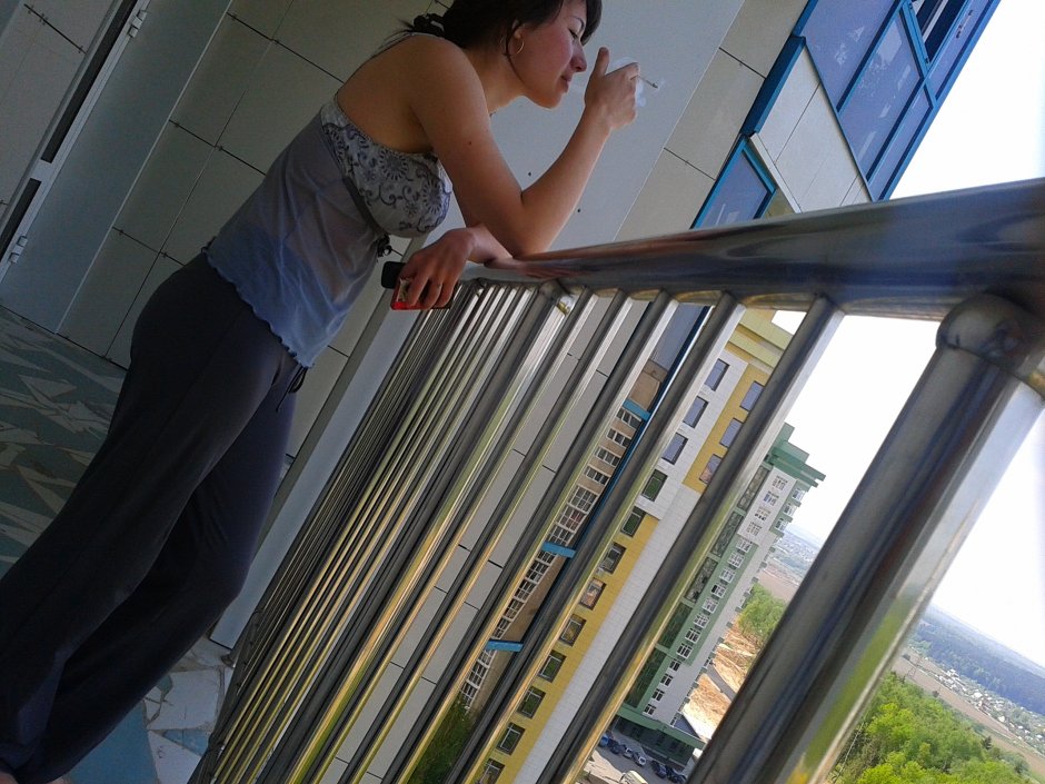Девушка курит на балконе