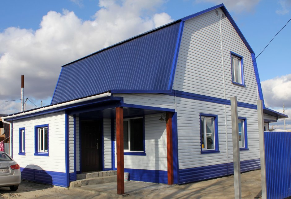 Дом с синей крышей обшитый сайдингом