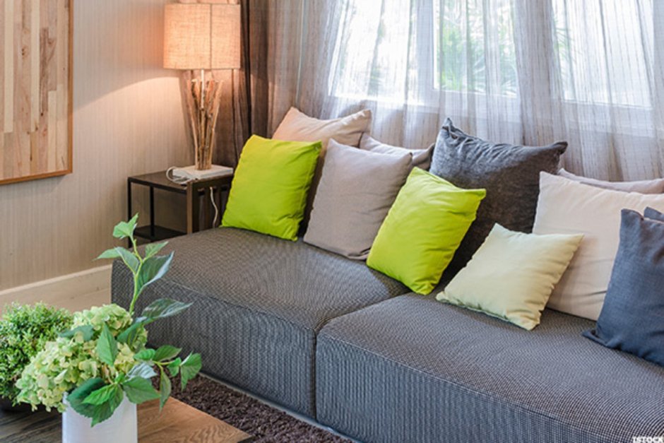 Серый диван с зелеными подушками