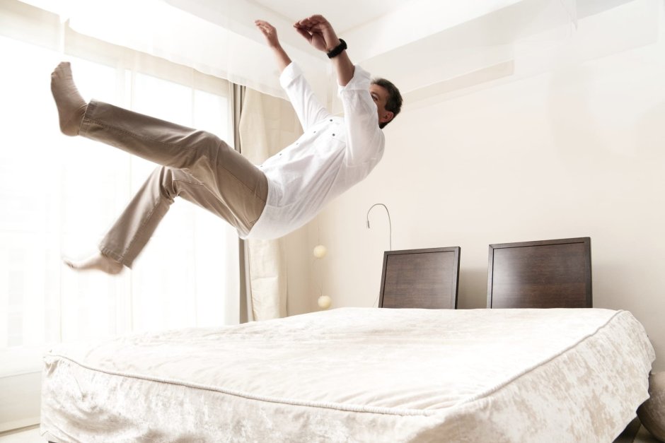 Человек прыгает на кровати
