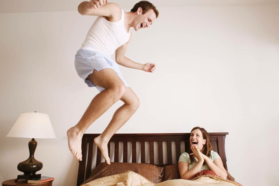 Мужчина и женщина прыгают на кровати