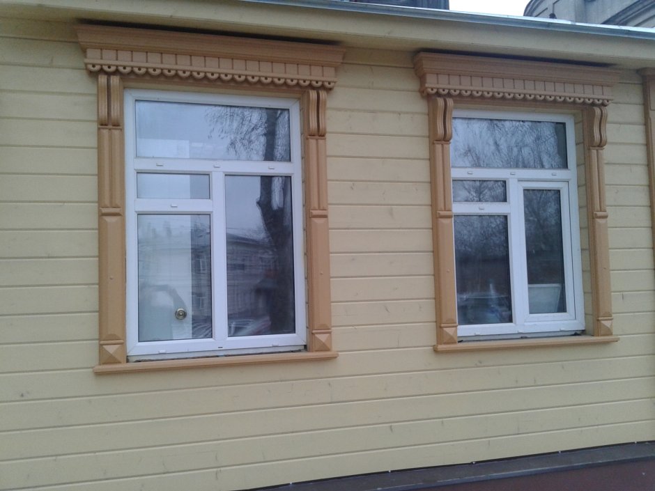 Кирпичный дом с деревянными наличниками на окнах