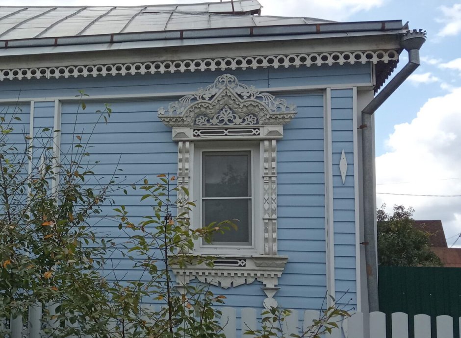 Кирпичный дом с деревянными наличниками на окнах