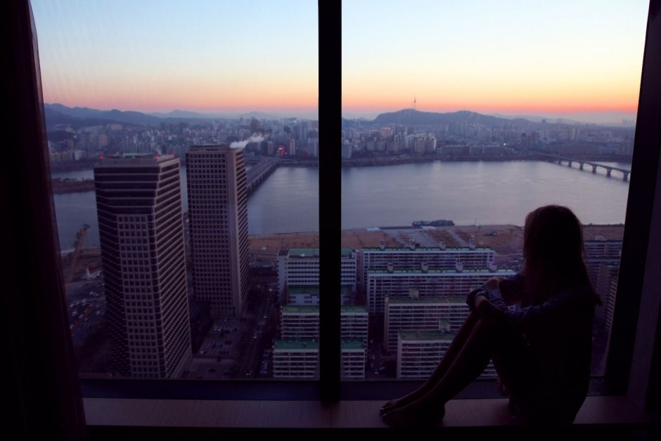 Девушка у окна с видом на город