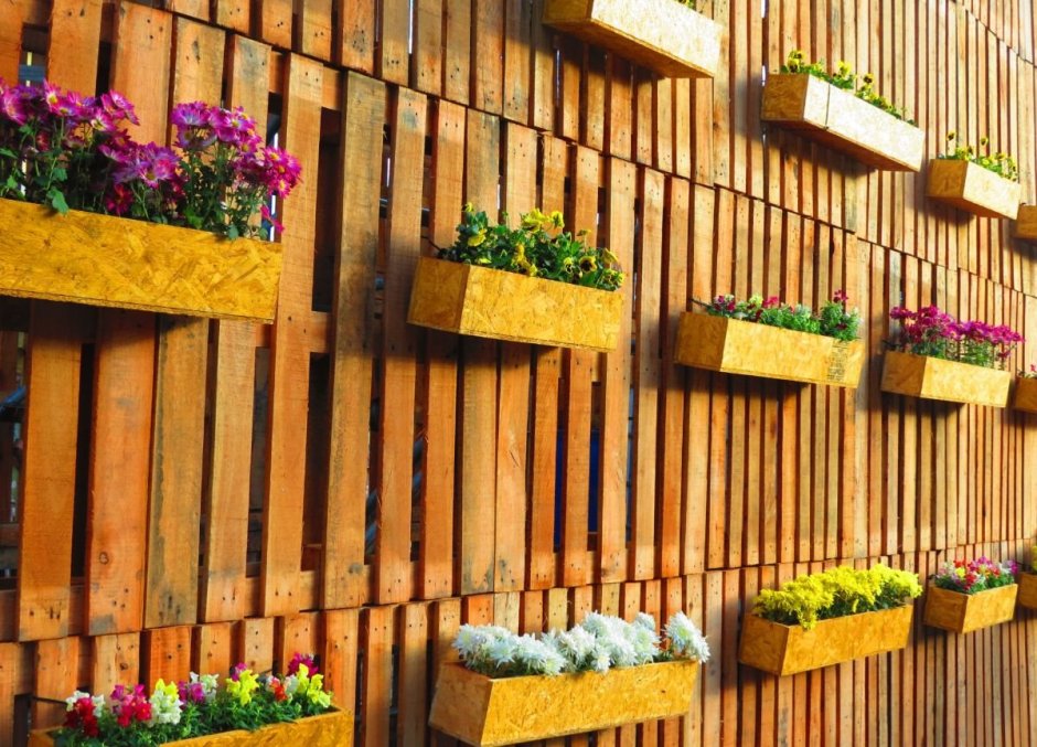 Горшки с цветами на деревянном заборе заборе