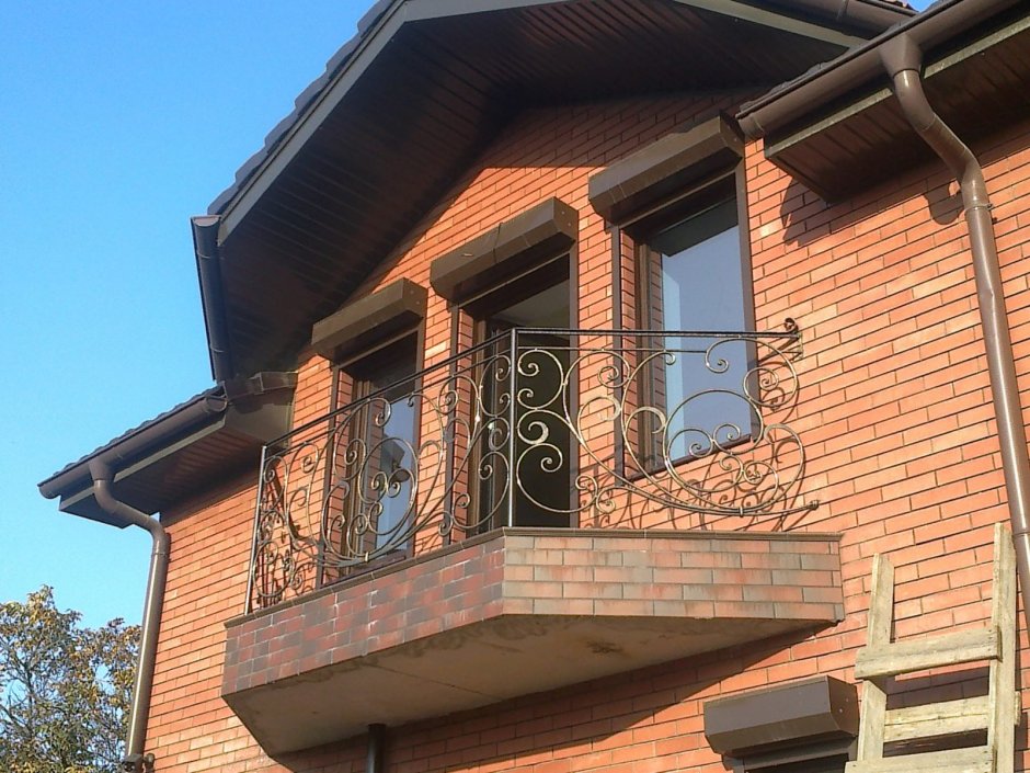 Дом из красного кирпича с кованым балконом