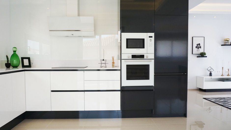 Белая кухня черной столешницей и белым холодильником