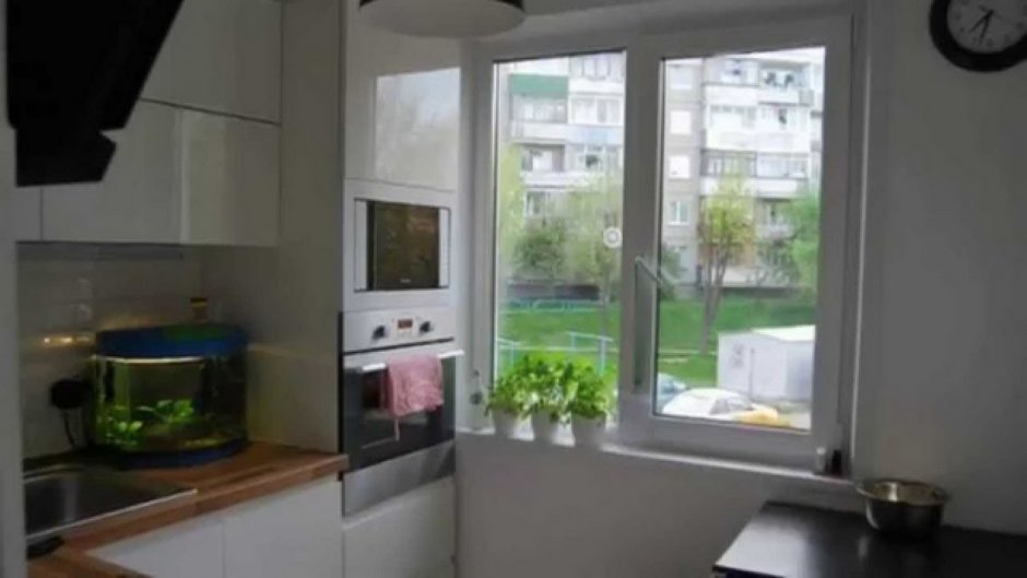 Холодильник у окна в маленькой кухне
