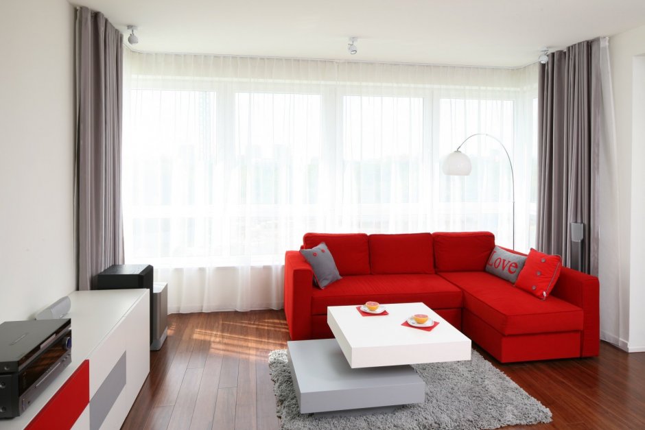 Интерьер маленькой гостиной с красным диваном
