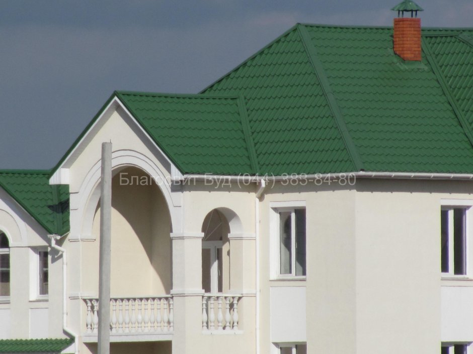Белый кирпичный дом с зеленой крышей