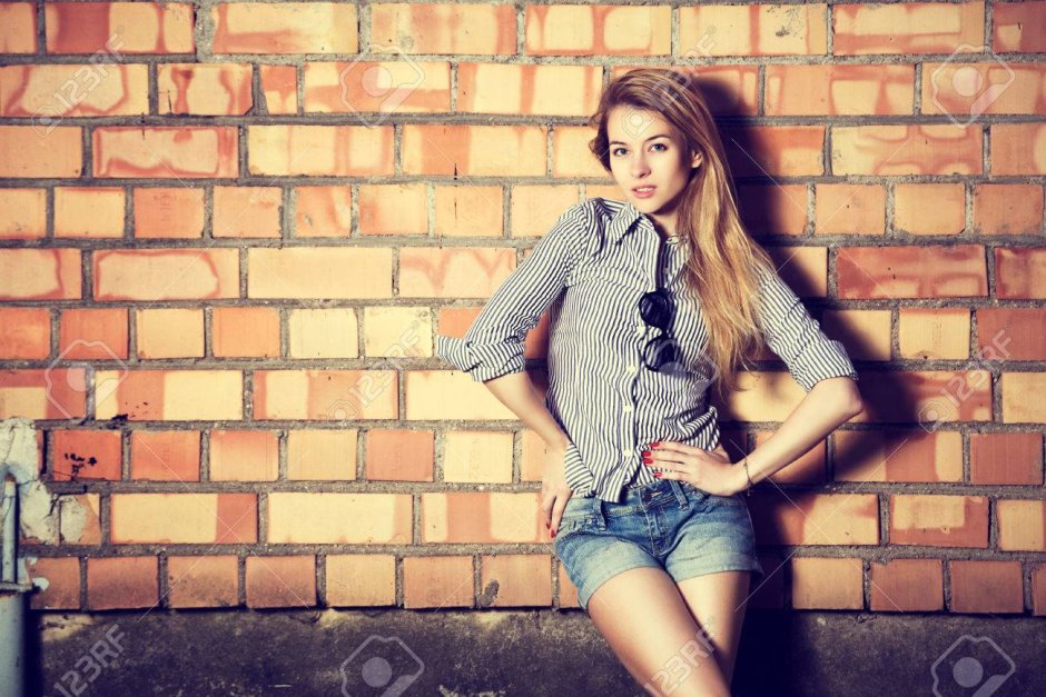 Стильная девушка на фоне кирпичной стены