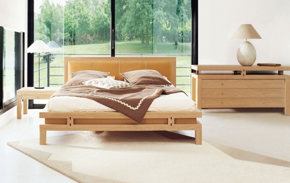 Деревянная низкая кровать на ножках в интерьере спальни