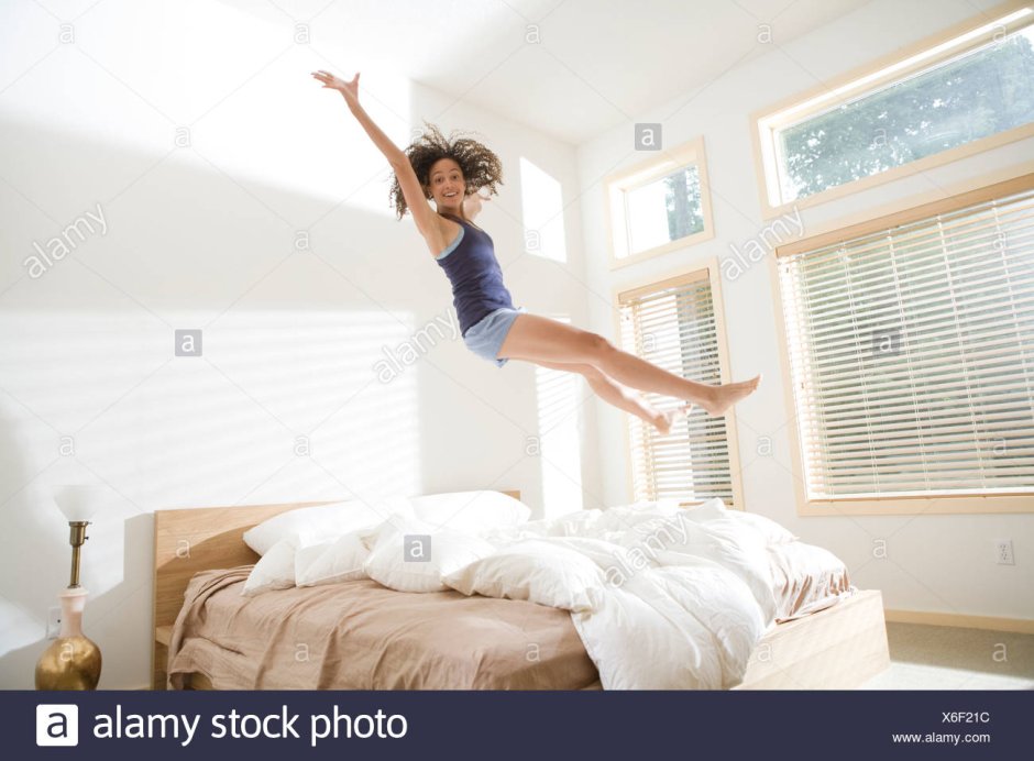 Девушка прыгает на кровати