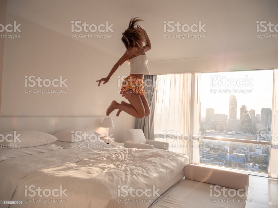 Женщина прыгает на кровати