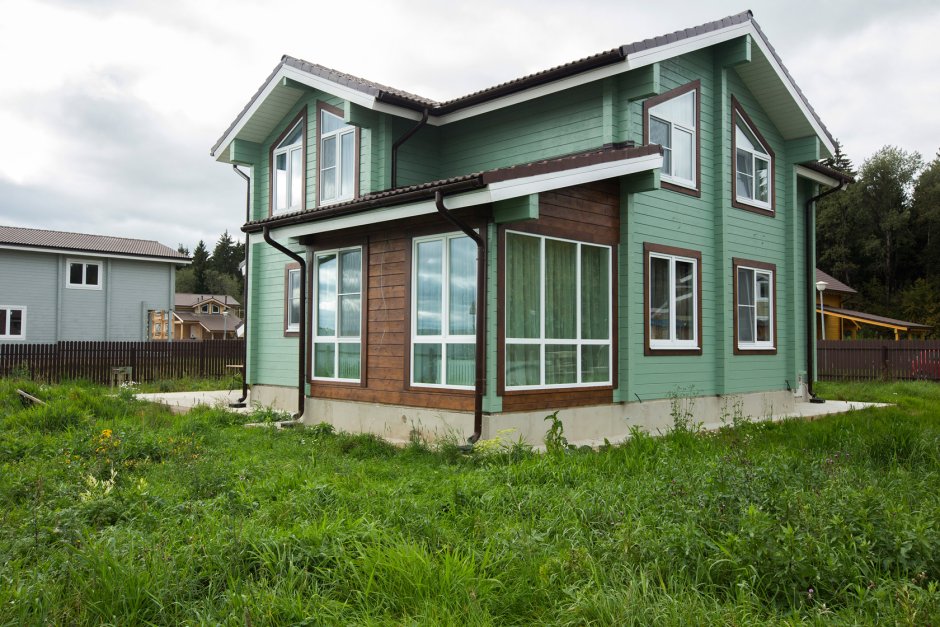 Двухэтажный кирпичный дом с зеленой крышей