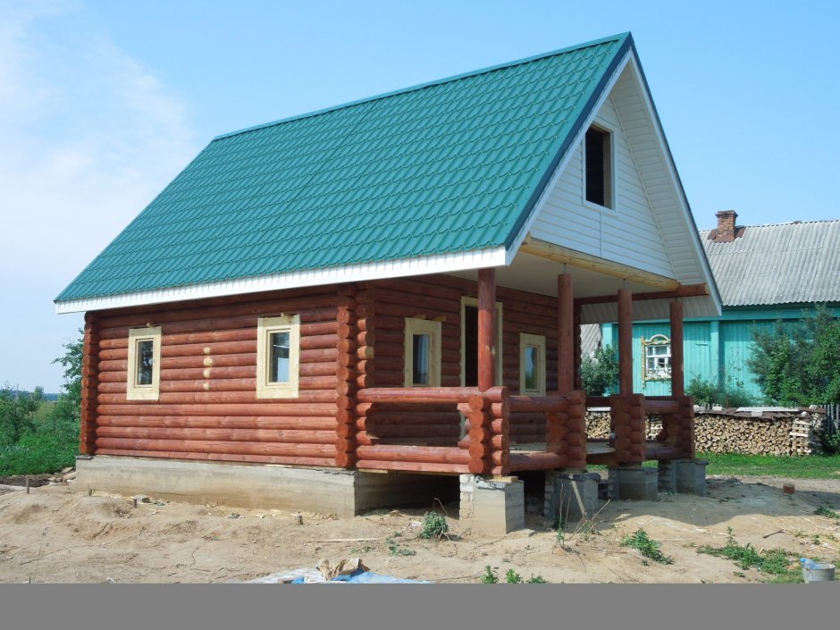 Рубленый дом с зеленой крышей
