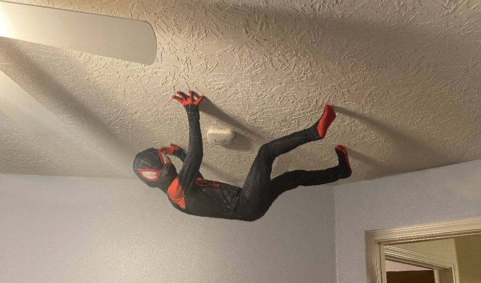 Человек паук карабкается по стене