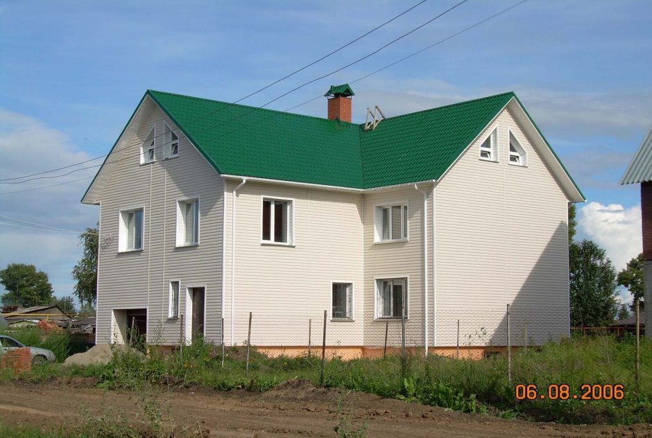 Дом из белого кирпича с зеленой крышей
